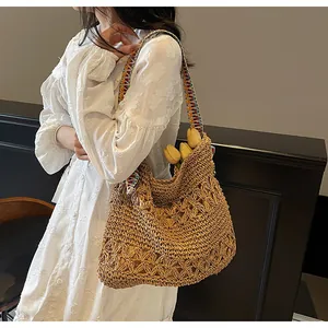Detail of hand-woven straw tote with colorful ethnic geometric strap and floral hollow texture
