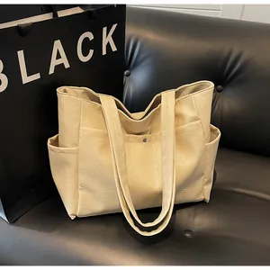 Macro shot of off-white tote bag showing pebbled leather texture and side pocket detail