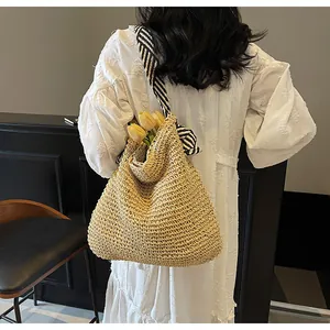 Detail of hand-woven straw tote bag with black and white striped canvas shoulder strap