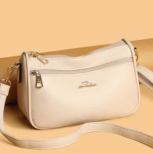 Macro detail of beige lychee grain leather crossbody bag and golden kangaroo logo