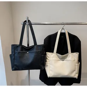 Detail view of large PU leather tote bags in black and beige with front pocket and buckle