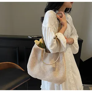 Detail of beige woven tote bag showing hollow mesh texture and wide fabric shoulder strap