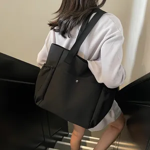 Large black nylon tote bag with silver buckles and drawstring side pockets for daily commuting
