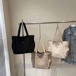 Three minimalist large canvas tote bags in black beige and off-white displayed on hangers
