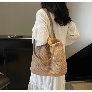 Close-up of wide strap and hand-woven texture on the brown straw shoulder tote bag