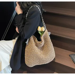 Detail of hand-woven straw tote bag with striped shoulder strap and rustic texture