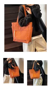Détail du sac cabas en toile orange montrant la poche latérale et le cordon blanc du zip