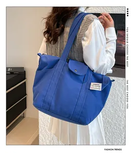 Detail of royal blue canvas tote bag with snap pocket and fashion label on shoulder strap