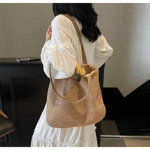 Detail of hand-woven beige straw tote bag with honeycomb texture and wide fabric shoulder strap