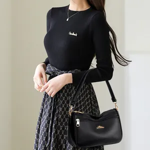 Minimalist black lychee texture crossbody bag with triple zipper and gold kangaroo logo