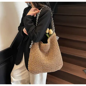 Detail of large woven straw tote bag with black and white striped scarf handle design