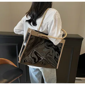 Detailed side view of black patent leather tote bag with thick rope shoulder strap and trim