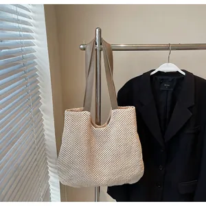 Detail of light beige woven tote bag with brown PU leather shoulder straps on a hanger