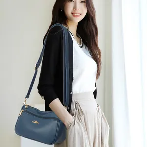 Minimalist navy blue leather crossbody bag with golden kangaroo logo and adjustable strap
