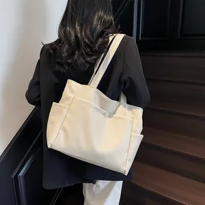 Minimalist large capacity cream tote bag with side pockets shown on a person