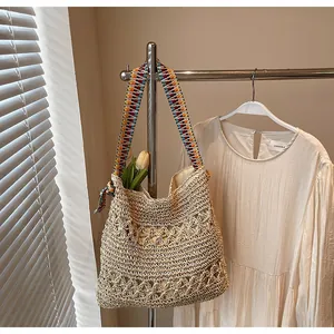 Detail of hand-woven straw tote with hollow floral patterns and colorful tassel straps