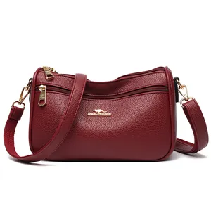 Minimalist burgundy pebbled leather crossbody bag with kangaroo logo and gold zippers