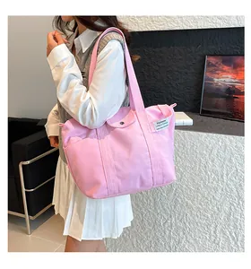Pink canvas tote bag shown as shoulder bag style on model with fashion tag detail