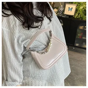 Détail du sac bandoulière rose avec chaîne décorative en perles et métal argenté