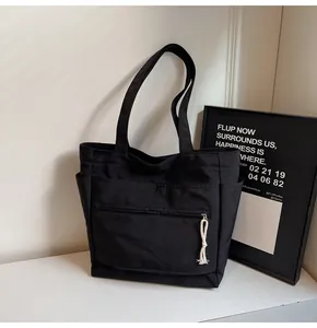 Détail du sac cabas en toile noire avec bandoulière large et poche à fermeture éclair
