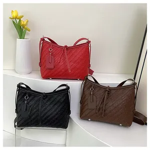 Detailansicht geflochtener Ledertaschen in Rot, Schwarz und Braun mit Metallfüßen