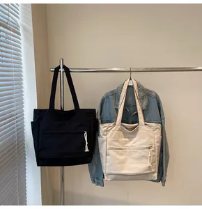 Vue détaillée de grands sacs cabas en toile noir et beige avec poches latérales et zips