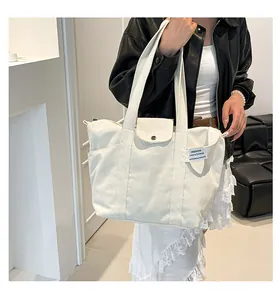 Detail of a cream canvas tote bag showing the magnetic snap pocket and side storage compartment