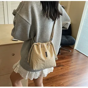 Detalle de bolso cubo beige en tela Oxford con cierre de cordón y etiqueta lateral