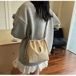 Detalle del bolso saco beige con cordón y etiqueta tejida SHUNUO en tela de nailon