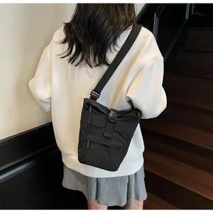 Detalle de bolso bandolera de nailon negro con correa ajustable y cierre de hebilla