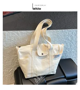 Detail view of a white canvas tote bag featuring front snap pockets and side pockets