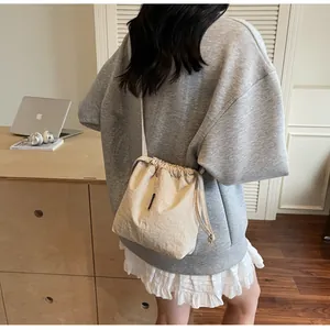 Detalle de bolso saco beige con cordón ajustable llevado por modelo en ambiente casual