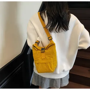 Detalle del bolso bandolera de nailon amarillo con cierre de hebilla negra y cordones