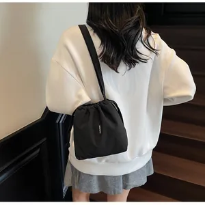 Detalle de un bolso tipo cubo negro con cordón que muestra su tejido de nailon texturizado