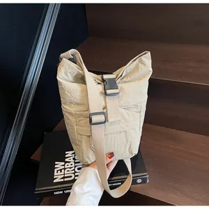 Detalle de bolso cubo de nailon beige con hebilla de plástico negro y correa de tela