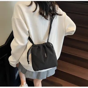 Detalle de bolso tipo cubo de tela Oxford negra con cordón ajustable en una modelo