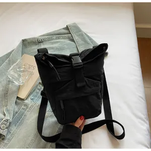 Detalle de bolso bandolera de nailon negro con hebilla sobre chaqueta vaquera
