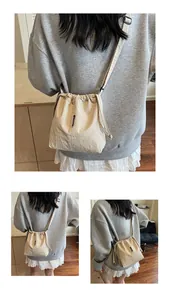 Detalle del cierre de cordón y correa ajustable en el bolso de hombro oxford beige
