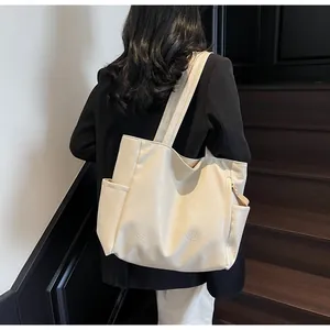 Detail of a large cream tote bag with wrinkled texture and side pocket on a model