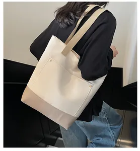 Detail of canvas tote bag with contrast stitching and metal rivet on front pocket