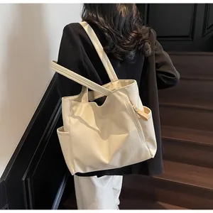 Detail of minimalist cream large tote bag featuring soft PU leather and side pocket