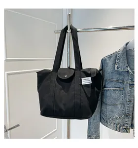 Detail of black canvas tote bag showing the magnetic snap closure and woven label logo