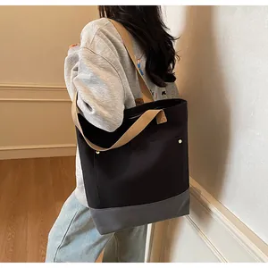 Detail of black canvas tote bag with gray patchwork and gold rivets in a lifestyle setting