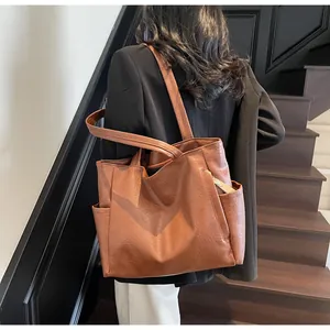 Detailed back view of a brown leather tote bag worn with a black blazer on stairs