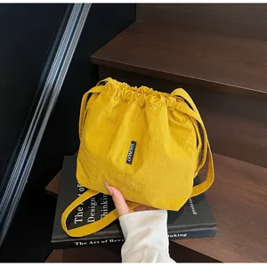Detalle del bolso de hombro amarillo de tela Oxford con cordón y etiqueta de marca SHUNUO