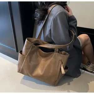 Detail view of large brown faux leather tote bag with functional side pockets and zip accent