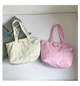 Detail of canvas tote bag with snap flap and fashion label, shown with casual items