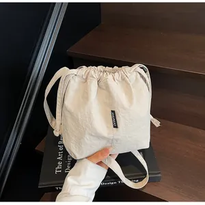 Primer plano del bolso saco de nailon blanco crema con cordón ajustable y logo SHUNUO