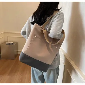 Macro view of large canvas tote bag featuring contrast stitching and metal rivet pockets