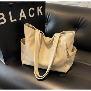 Close-up of the beige textured leather tote bag showing the side pocket and front zipper